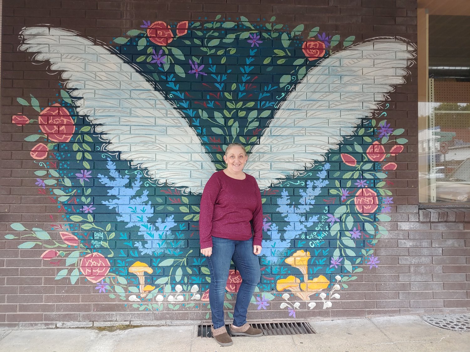Sharon Eastman, a 30-year employee of Spiffy’s Restaurant & Bakery who now works at M&K Town Store and Sweet Inspirations, poses for a photo in front of a mural.